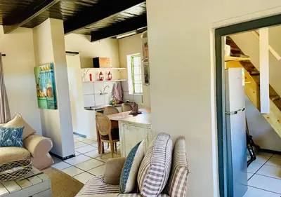 a living room with a couch and a kitchen at Kleine Vrede Farm Cottage in Hermanus