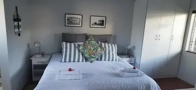 a bedroom with a white bed with two towels on it at Jasmine Cottage - Fast Wi-Fi, slow living in Hermanus