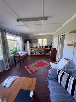 a living room with a blue couch and a table at Jasmine Cottage - Fast Wi-Fi, slow living in Hermanus