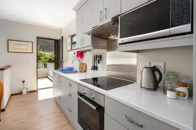 a kitchen with white cabinets and a stove top oven at Steenbok House in Hermanus