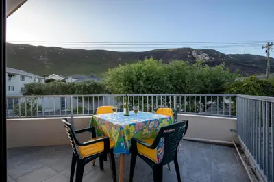 a table and chairs on a balcony with a view at Steenbok House in Hermanus