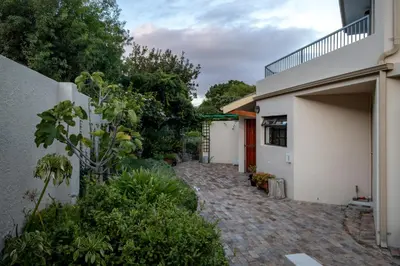 a house with a brick walkway next to a building at Steenbok House in Hermanus