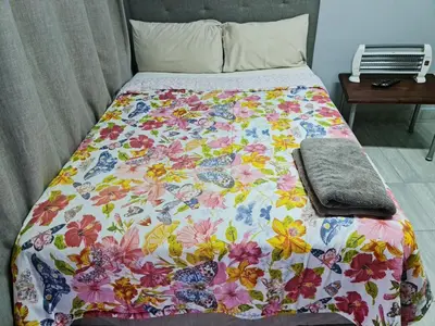 a bed with a flowered blanket on it at Hasate Guest House 10 Florence street Oakdale Belliville 7530 cape town south African in Cape Town