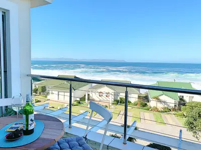 a balcony with a table and chairs and the ocean at 49 Whalerock in Hermanus