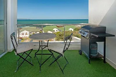 a table and two chairs on a balcony with a grill at 49 Whalerock in Hermanus