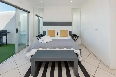 a bedroom with a large bed and a balcony at 49 Whalerock in Hermanus