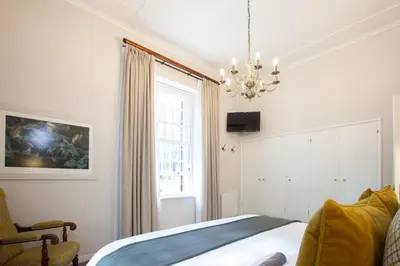 a bedroom with a bed and a window and a chandelier at Elgin Vintners Country House in Elgin