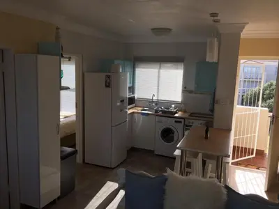 a kitchen with a refrigerator and a sink and a table at Huisi by di C in Hermanus