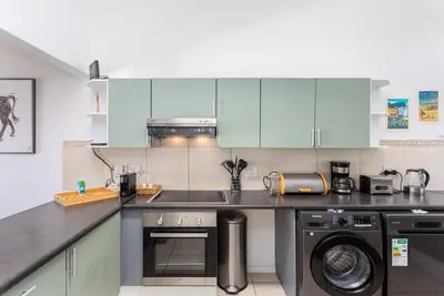 a kitchen with blue cabinets and a washer and dryer at Sea Spray B403 by CTHA in Bloubergstrand