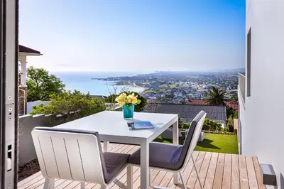 a white table and chairs on a balcony with a view at Kianga in Gordonʼs Bay