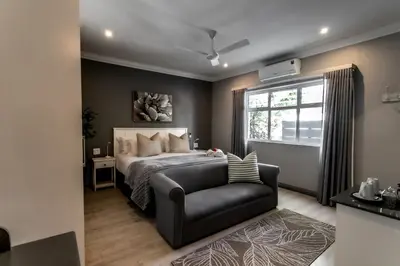 a bedroom with a bed and a chair and a window at Whale Coast Ocean Villa in Hermanus