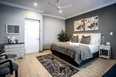 a bedroom with a bed and a dresser and a window at Whale Coast Ocean Villa in Hermanus