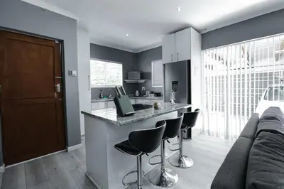 a kitchen with a bar with stools and a couch at Milo's Sky Grey Guest House - No Load shedding in Cape Town