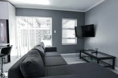 a living room with a couch and a flat screen tv at Milo's Sky Grey Guest House - No Load shedding in Cape Town