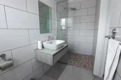 a white bathroom with a sink and a mirror at Milo's Sky Grey Guest House - No Load shedding in Cape Town