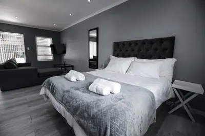 a bedroom with a large bed with two towels on it at Milo's Sky Grey Guest House - No Load shedding in Cape Town