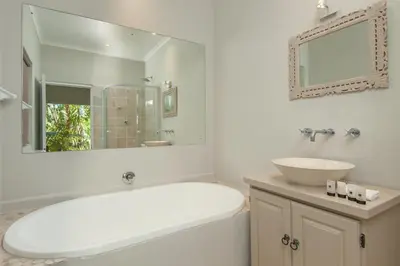 a white bathroom with a tub and a sink at Villa Blu Guesthouse in Hermanus