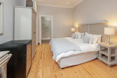a bedroom with a large white bed and a desk at Villa Blu Guesthouse in Hermanus