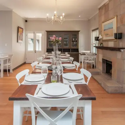 a dining room with a long table and white chairs at Villa Blu Guesthouse in Hermanus