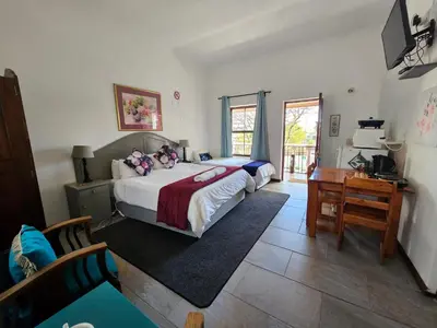 a bedroom with a bed and a desk and a desk at Kelkiewyn Guesthouse Caledon in Caledon