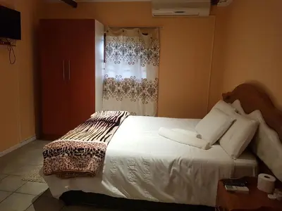 a bedroom with a white bed with a window at Canterbury Self-catering in Bellville