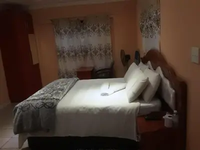 a bedroom with a large bed with white sheets and pillows at Canterbury Self-catering in Bellville