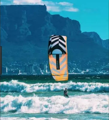 a person standing in the ocean with a kite at Sea Spray in Bloubergstrand