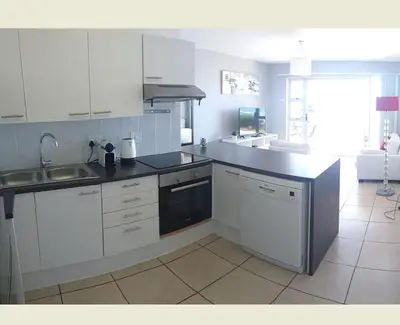a kitchen with white cabinets and a sink and a counter at Sea Spray in Bloubergstrand