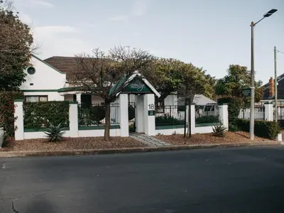 a white house with a tree in front of a street at Cummings Guesthouse in Wellington