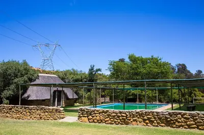 a swimming pool with a stone wall next to a building at Steenbok Farm Cottages Steenbok cottage in Wolseley