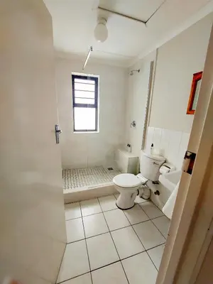 a white bathroom with a toilet and a window at Broadway Self Catering Apartments in Durbanville