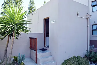 a stairway leading to a white house with a palm tree at Broadway Self Catering Apartments in Durbanville