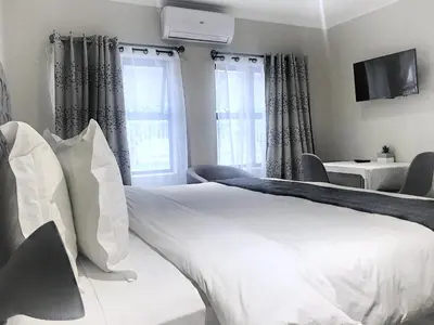 a bedroom with a large white bed and a table at Selton Guesthouse in Cape Town