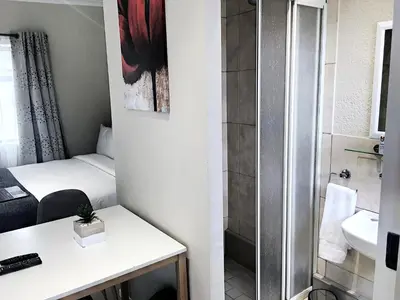 a small bathroom with a bed and a shower at Selton Guesthouse in Cape Town