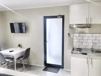 a small kitchen with a white table and a door at Selton Guesthouse in Cape Town