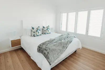 a white bedroom with a bed and a window at Voir la Mer - Blouberg Beach in Bloubergstrand