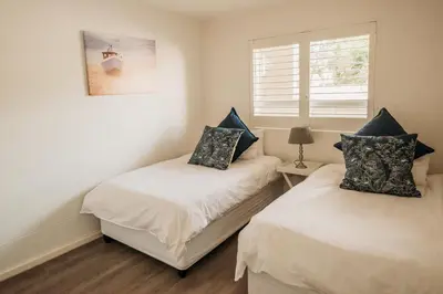 two twin beds in a room with a window at Voir la Mer - Blouberg Beach in Bloubergstrand