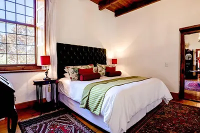 a bedroom with a bed and a large window at Cape Dutch @ Keerweder in Franschhoek