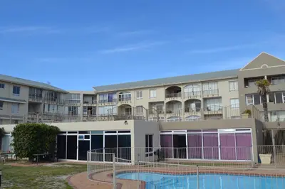 a building with a swimming pool in front of it at Lagoon Beach Neptune Isle Cape Town in Cape Town