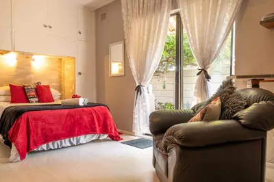 a bedroom with a bed and a couch and a window at Angel's Corner in Cape Town