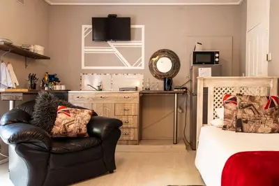 a bedroom with a leather chair and a kitchen at Angel's Corner in Cape Town