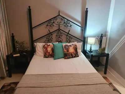 a bed with a black head board and pillows at Angel's Corner in Cape Town