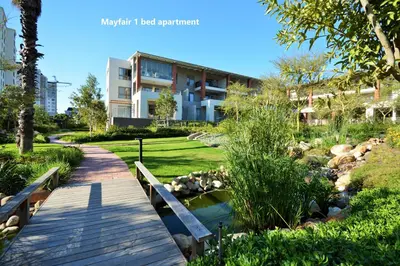 a bridge over a river in a park with a building at Century City Boutique Apartments in Cape Town