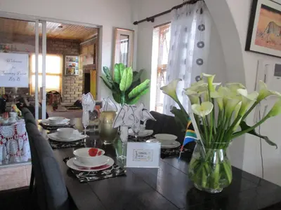 a dining room table with flowers and plates on it at Turning Point Bed & Breakfast in Cape Town