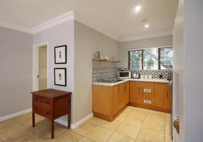 a kitchen with wooden cabinets and a sink and a window at Stony Brook Cottages in Franschhoek
