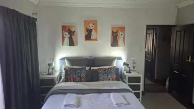 a bedroom with a bed with paintings of cats on the wall at Robert's Place Paarl in Paarl