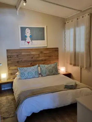a bedroom with a large bed with a wooden headboard at Potluck Cottage in Hermanus