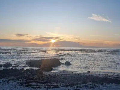 a sunset over the ocean with the sun setting at Potluck Cottage in Hermanus