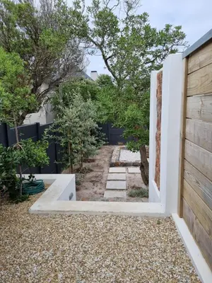 a backyard with a wooden fence and a driveway at Potluck Cottage in Hermanus