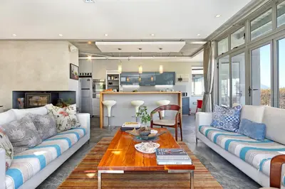 a living room with two couches and a table at Atlantic Blue Villa at Pilots in Cape Town